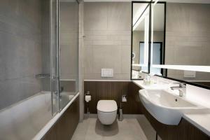 a bathroom with a toilet and a sink and a shower at Courtyard by Marriott Katowice City Center in Katowice