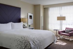 a bedroom with a large white bed and a pink chair at Renaissance Las Vegas Hotel in Las Vegas