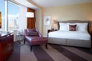 a bedroom with a bed and a chair and a window at Renaissance Las Vegas Hotel in Las Vegas