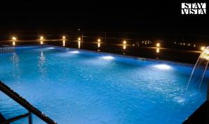 a large swimming pool at night with a fountain at StayVista at Sasha Farms in Roha with Pool, WiFi in Roha