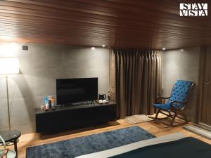 a living room with a tv and a blue chair at StayVista at Sasha Farms in Roha with Pool, WiFi in Roha