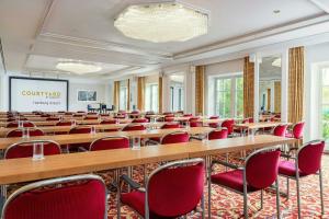 a conference room with tables and chairs and a screen at Courtyard by Marriott Hamburg Airport in Hamburg +29 photos