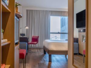 a hotel room with a bed and a desk and a window at Novotel Barcelona City in Barcelona