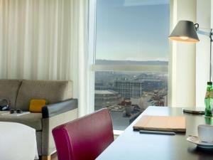 a room with a table and a couch and a window at Novotel Barcelona City in Barcelona