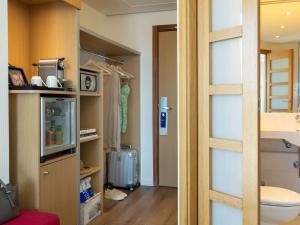 a room with a closet with a toilet and a door at Novotel Barcelona City in Barcelona