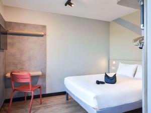 a bedroom with a bed and a red chair at ibis budget Issy Les Moulineaux Paris Ouest in Issy-les-Moulineaux