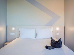 a white bed with a bag on top of it at ibis budget Issy Les Moulineaux Paris Ouest in Issy-les-Moulineaux