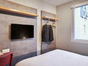 a bedroom with a bed and a flat screen tv at ibis budget Issy Les Moulineaux Paris Ouest in Issy-les-Moulineaux