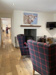 ein Wohnzimmer mit zwei Stühlen und einem Kamin in der Unterkunft Sherrabeg Cottage in Laggan