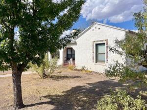 a white house with a tree in front of it at Courthouse Corner - Beautiful adobe, pet friendly in Marfa