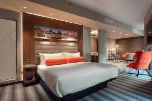 ein Hotelzimmer mit einem großen Bett und einem roten Stuhl in der Unterkunft Aloft Dublin City in Dublin