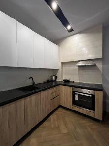 Una cocina con gabinetes blancos y encimeras negras. en Jasmine Apartment, en Golem