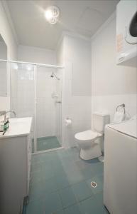 a white bathroom with a shower and a toilet at Franklin Apartments in Adelaide