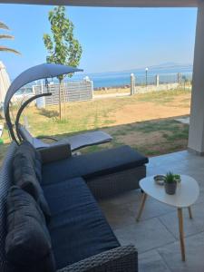 a blue couch and an umbrella on a patio with the beach at By the sea in Nea Potidaea