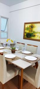 a dining room table with chairs and a painting on the wall at Apto 3 Quartos com Suíte e 3 Banheiros em Guarapari in Guarapari