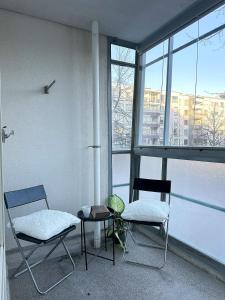 two chairs and a table in a room with windows at 3BR w balconies and private sauna in Helsinki