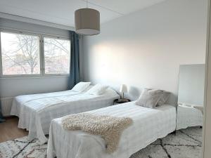 two beds in a white room with a window at 3BR w balconies and private sauna in Helsinki