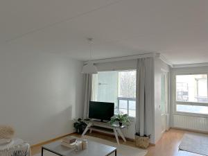 a white living room with a television and a table at 3BR w balconies and private sauna in Helsinki