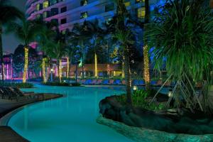 a swimming pool with palm trees and a building at Le Méridien Kuala Lumpur in Kuala Lumpur