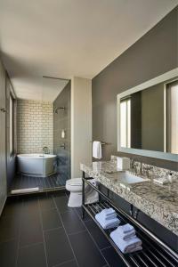 a bathroom with two sinks and a tub and a toilet at Renaissance Saint Elm Dallas Downtown Hotel in Dallas
