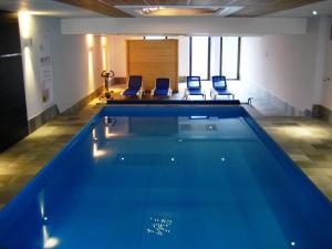 a swimming pool in a room with two chairs at Hotel Restaurant Aux Trois Roses in La Petite-Pierre