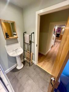 Un baño con lavabo y espejo y un pasillo. en Stalkers Cottage, en Spean Bridge 9 fotos más