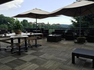a restaurant with tables and umbrellas on a patio at Logis Hôtel-Restaurant Aux Trois Roses in La Petite-Pierre
