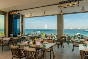 - un restaurant avec des tables et des chaises et une vue sur l'eau dans l'établissement Aloft Palm Jumeirah, à Dubaï