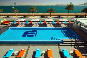 - une piscine avec chaises longues et parasols et l'océan dans l'établissement Aloft Palm Jumeirah, à Dubaï