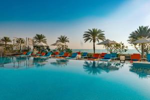 une grande piscine avec chaises et parasols dans l'établissement Aloft Palm Jumeirah, à Dubaï