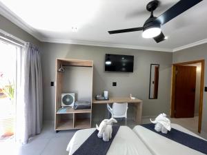 a bedroom with two beds and a desk and a ceiling fan at The Mole Guesthouse in Swakopmund