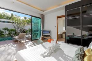 a bedroom with a large bed and a television at La Ville Phuket Pool Villa in Nai Yang Beach