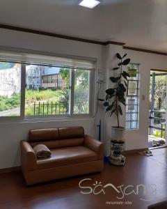ein Wohnzimmer mit einer Couch und zwei Fenstern in der Unterkunft Sanjang Guest House in Baguio City