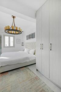 Un dormitorio blanco con una cama grande y una lámpara de araña. en Mykonos Muse, en Mykonos ciudad