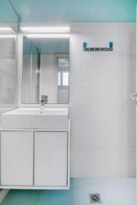 Un baño blanco con lavabo y ducha. en Mykonos Muse, en Mykonos ciudad
