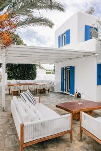 un patio con muebles blancos y una casa blanca en Mykonos Muse, en Mykonos ciudad