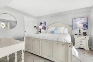 a white bedroom with a bed and a mirror at El Matador 513 in Fort Walton Beach +41 photos