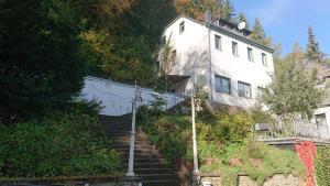 a white house with stairs leading up to it at Ferienzimmer by Riela im ehemaligem Hotel Schöneck in Schönecken