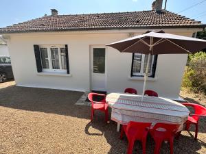a table and chairs with an umbrella in front of a house at La petite maison des gîtes de Joséphine in Saint-Dyé-sur-Loire