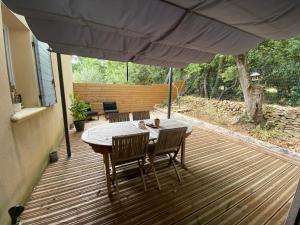 a table and chairs on a deck with an umbrella at Appartement en campagne in Saint-Marcel-de-Carreiret