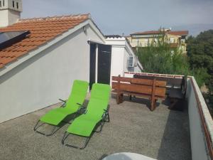 two green chairs and a bench on a balcony at Villa Terraca in Mandre