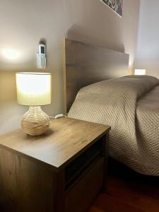 Casa SantaにあるLa Rosa sul Mareのベッド横の木製テーブルの灯り