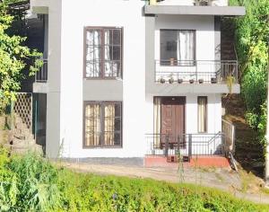 a white house with a porch and a balcony at Villa White Orchid in Hatton