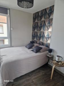 une chambre avec un grand lit blanc avec des oreillers bleus dans l'établissement Les chambres de l'auberge, à Watten 14 autres photos