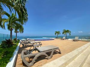 卡塔赫纳Apartment with direct access to the Sea in CTG的一个带椅子的庭院、一个游泳池和大海