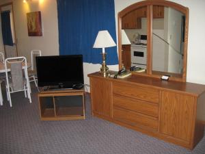 a room with a desk with a television and a mirror at Pals Motel and RV Park in Medicine Hat