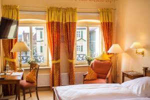 een hotelkamer met een bed, een bureau en ramen bij WAGNERS Hotel Greifen-Post in Feuchtwangen