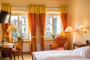 フォイヒトヴァンゲンにあるWAGNERS Hotel Greifen-Postのベッド、デスク、窓が備わるホテルルームです。
