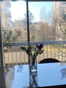 a vase with flowers on a table in front of a window at Cosy et Arty in Paris +9 photos
