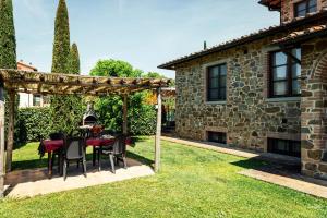 a table and chairs under a pergola in a backyard at Agriturismo Casal Gheriglio in Lucignano
